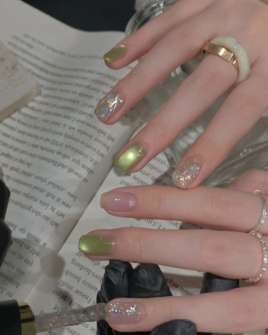 Un pennello applica uno strato di smalto gel glitterato argento denso su ununghia daccento.