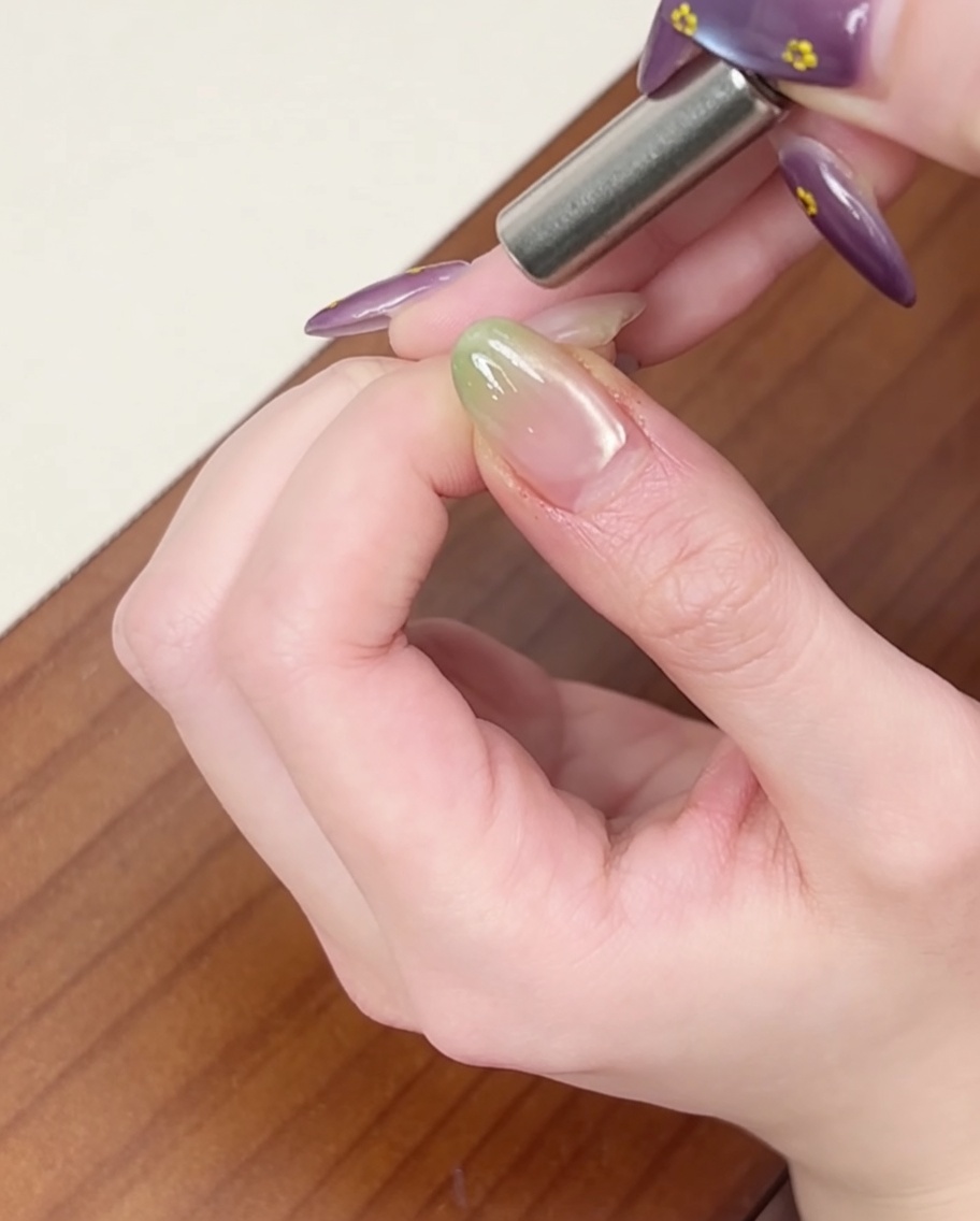 Un magnete cilindrico tenuto vicino al lato dellunghia per creare un effetto cat-eye.