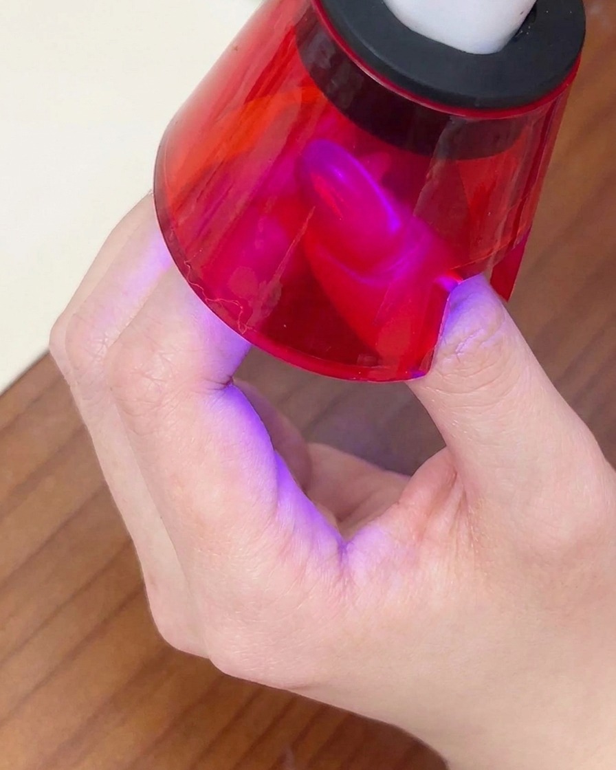 Ununghia finita polimerizzata sotto una piccola lampada UV portatile rossa.