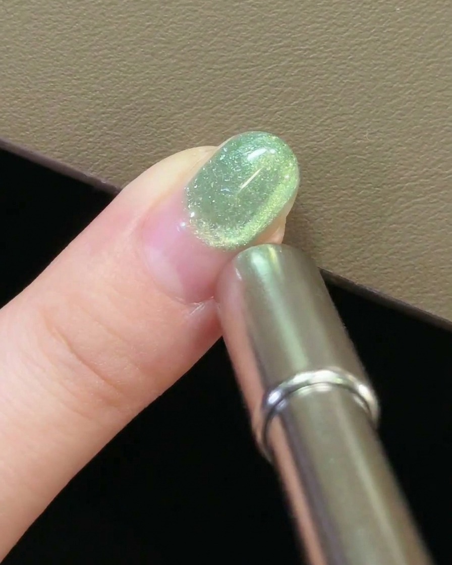 Una vista ravvicinata di un magnete che passa sopra ununghia, creando un movimento circolare nel gel cat-eye.
