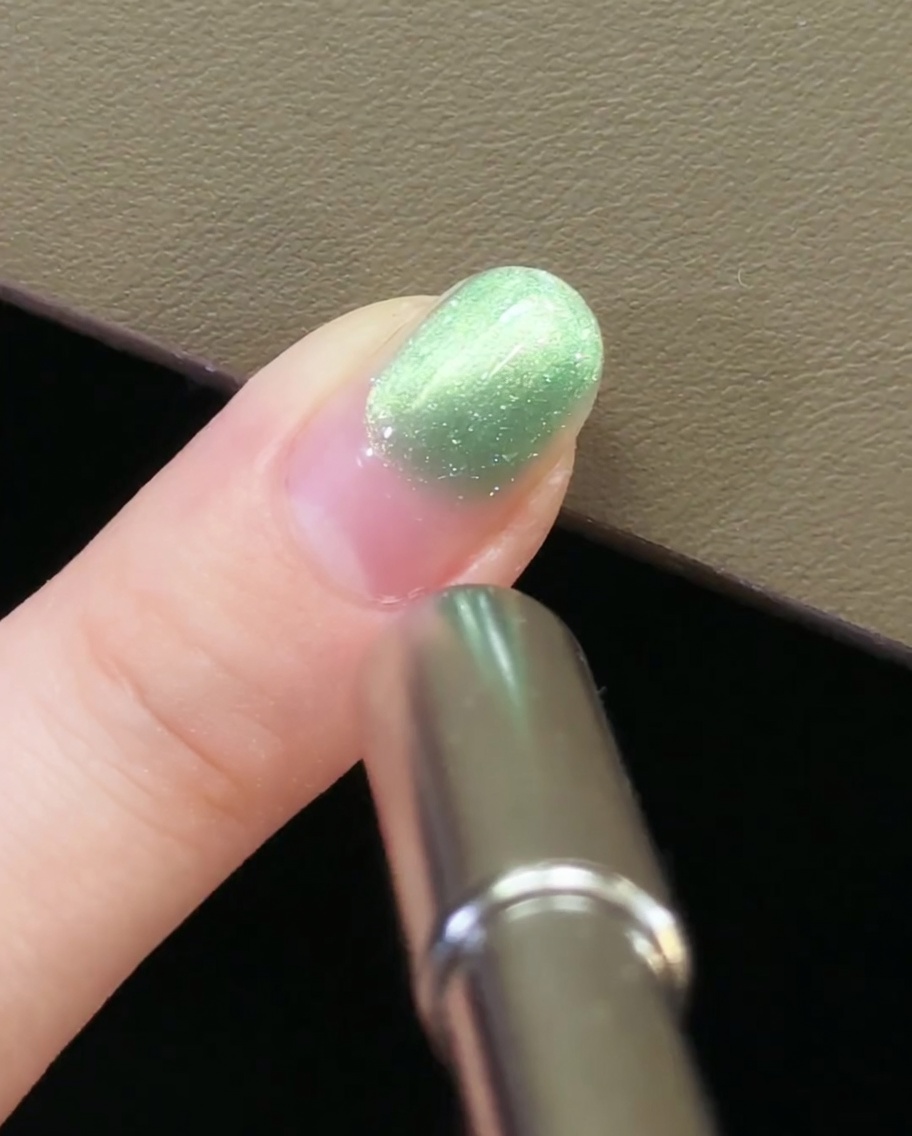 Una mano che allontana lo strumento magnetico dallunghia per bloccare il motivo cat-eye.
