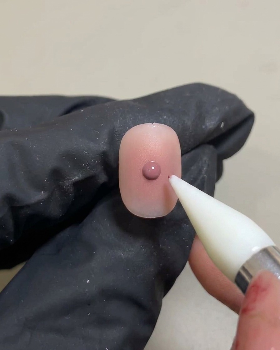 Strumento in silicone che applica una piccola goccia concentrata di gel rosa sopra il gradiente già polimerizzato.