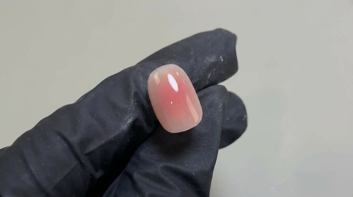 Una manicure in gel con un delicato effetto blush sfumato rosa su unghie corte arrotondate e finitura ultra brillante.