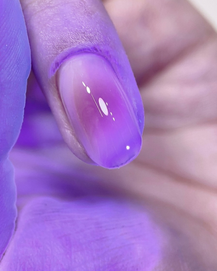Ununghia blush rosa perfettamente curata che polimerizza sotto la luce viola di una lampada UV/LED.