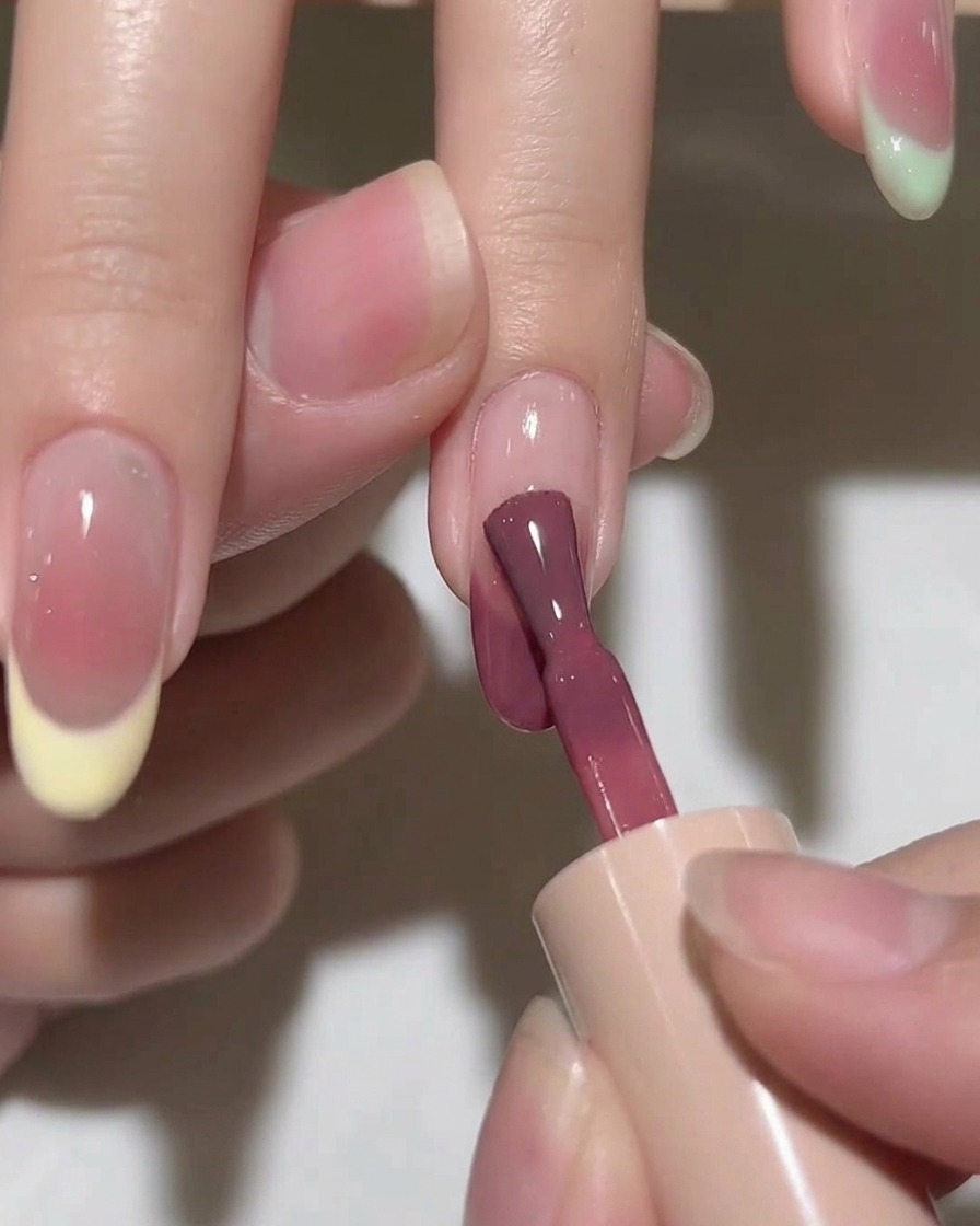 Un pennello sfuma una goccia di gel rosa sullunghia, creando un effetto circolare morbido e diffuso.