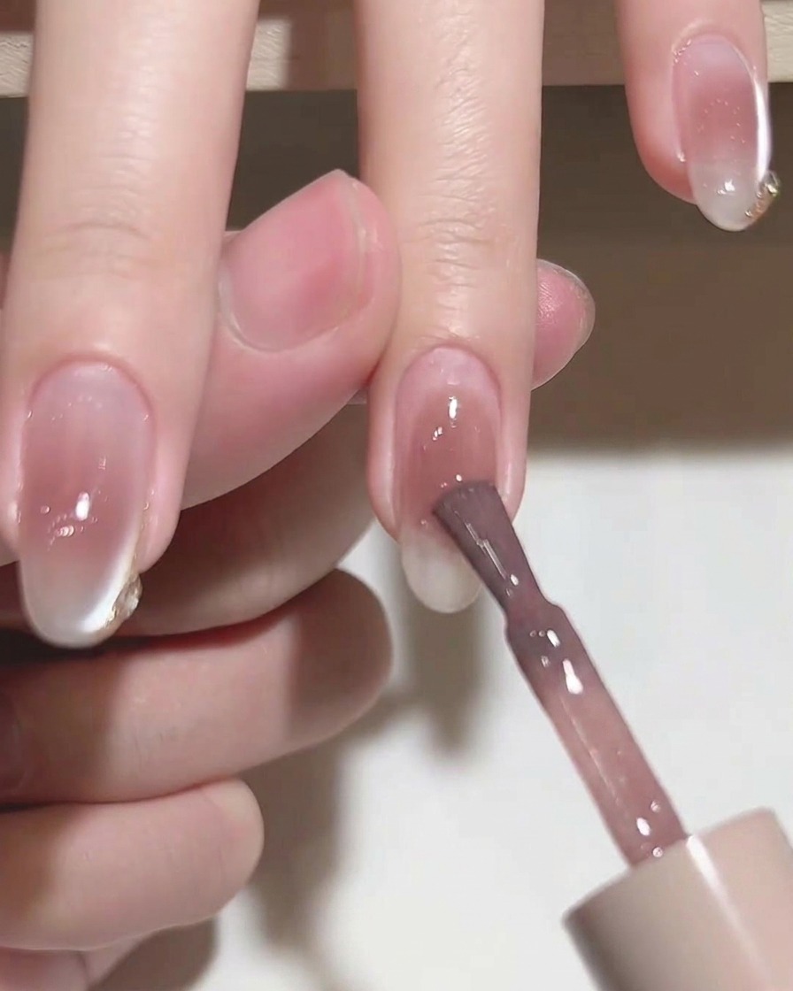 Un pennello piatto che livella lo smalto gel rosa su ununghia.