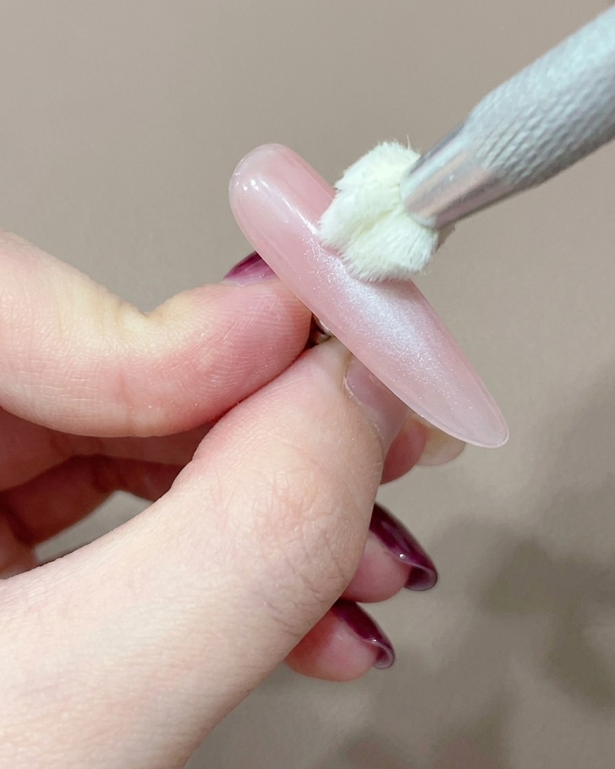 Uno strumento applicatore in silicone che aggiunge con cura un punto concentrato di gel rosa al centro dellunghia.