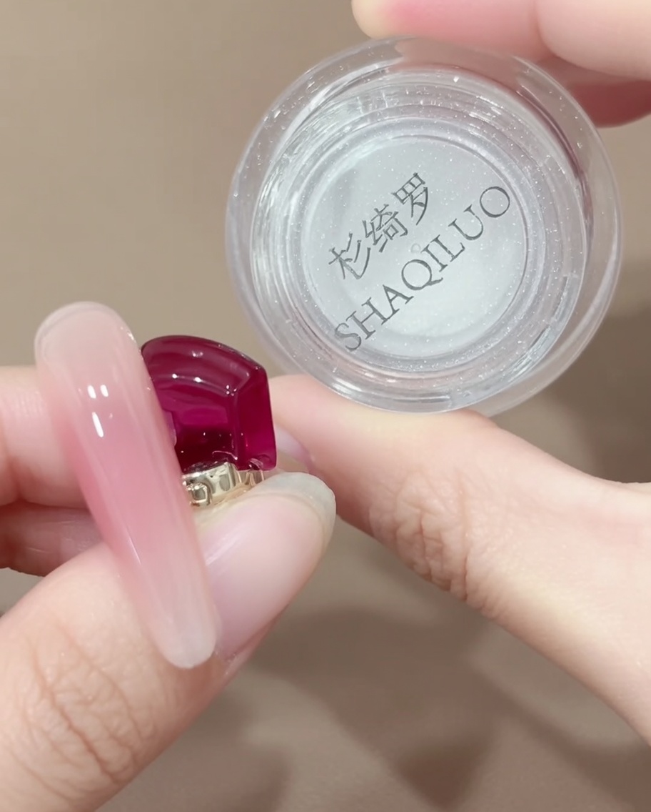 Uno strumento applicatore con punta in silicone che preleva una piccola quantità di polvere cromo iridescente da un barattolino.
