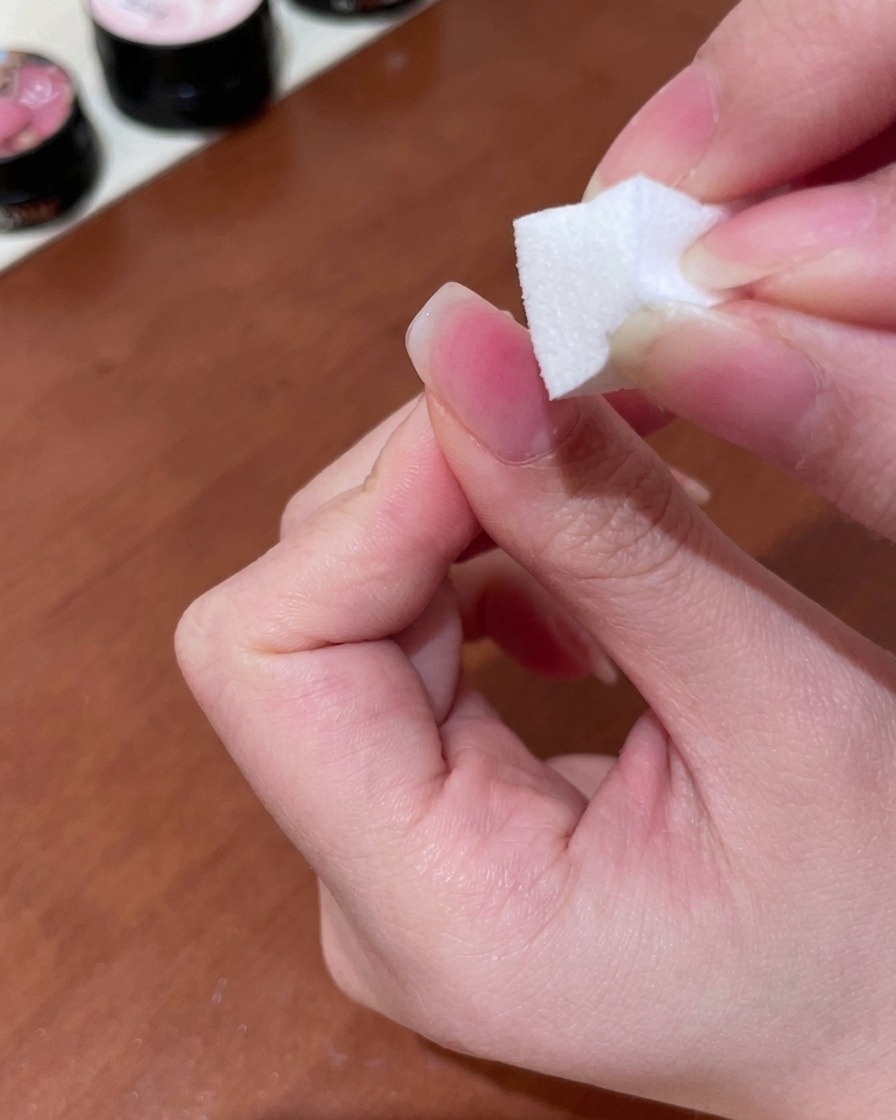 Una spugnetta da trucco utilizzata per picchiettare e sfumare il gel pesca in un delicato gradiente sullunghia.