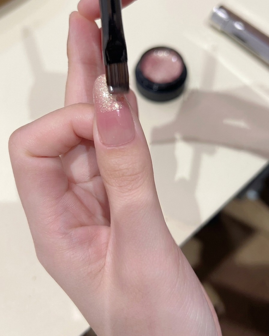 Un piccolo pennello che applica gel cat eye sulla punta di ununghia, sfumandolo leggermente verso il centro.