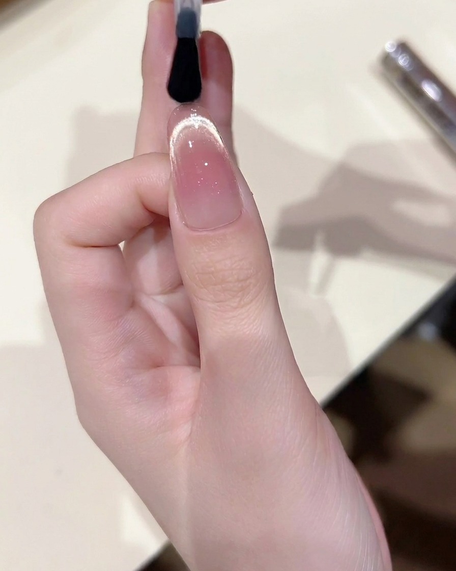 Un pennello che applica un top coat finale ad alta lucentezza sopra il design cat eye completato.