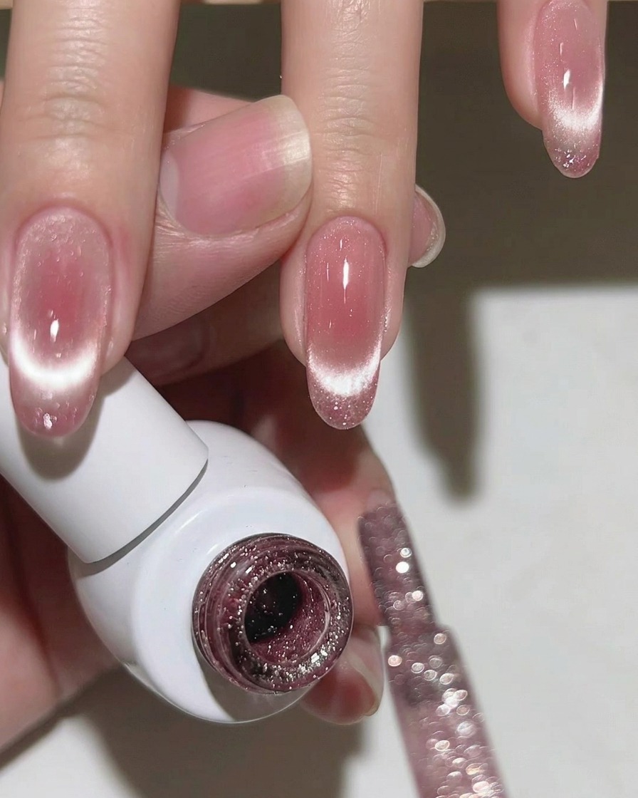 Primo piano di ununghia che mostra una linea cat-eye vibrante e concentrata sulla punta sopra una base rosa tenue.