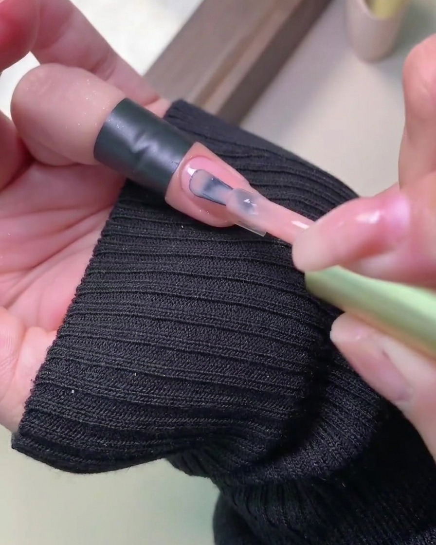 Primo piano che mostra una seconda passata di smalto gel colorato applicata uniformemente sopra lo strato precedentemente catalizzato.