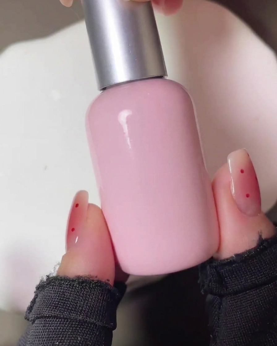 Le unghie che vengono polimerizzate sotto una lampada UV dopo lapplicazione iniziale del pigmento blush rosso.