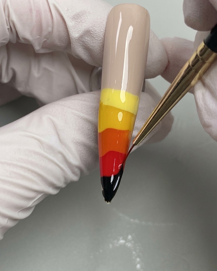 Un pennello a punta fine trascina i colori gel bagnati verso lalto per creare fiamme.