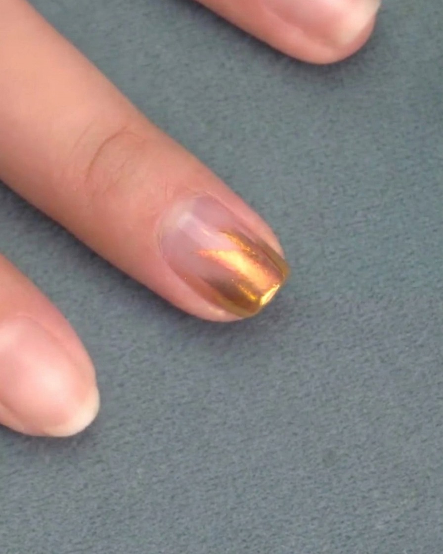 Un pennello stende un secondo strato di smalto gel rosa sopra il precedente.