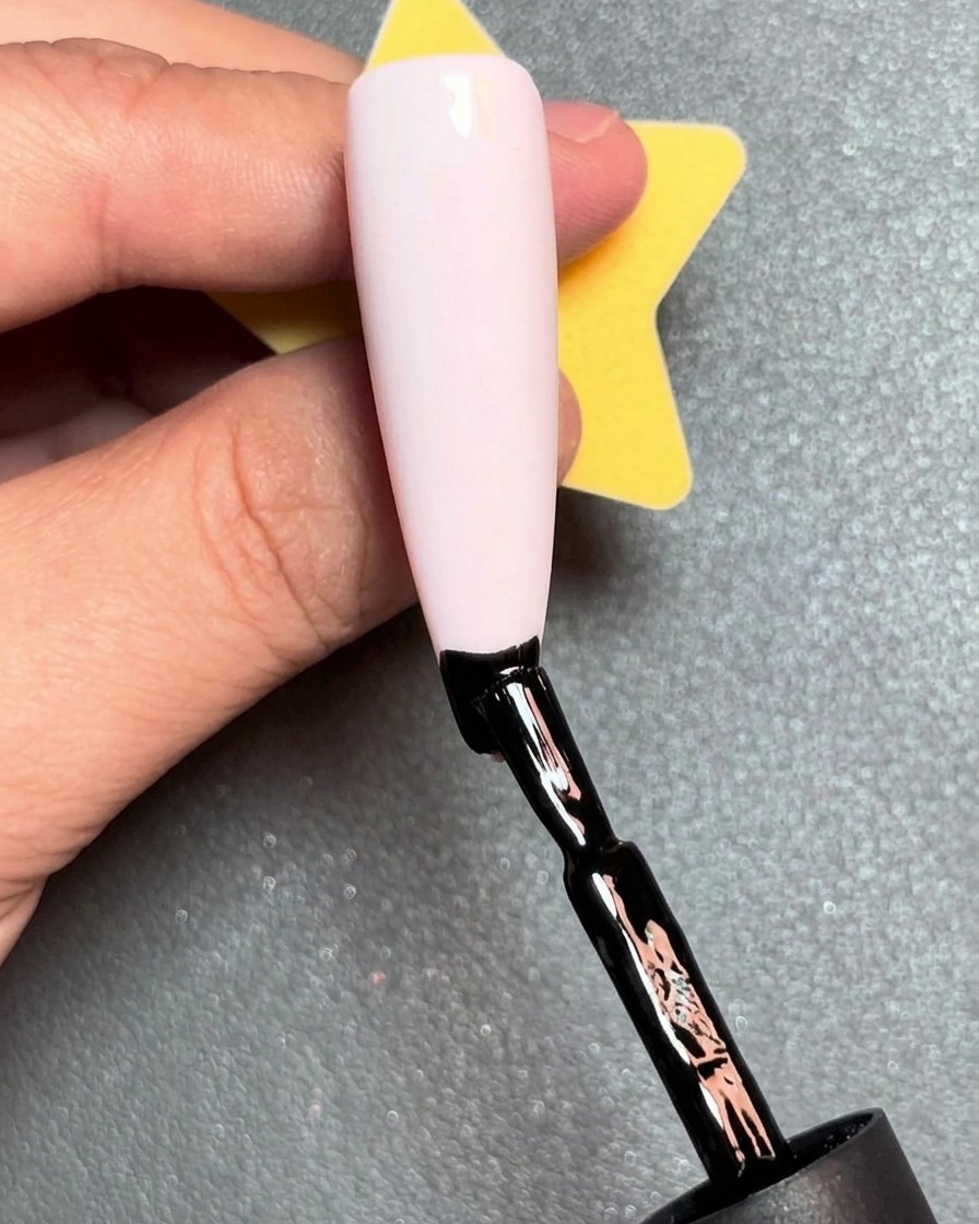 Un pennello applica una linea rossa di smalto gel appena sopra la linea nera sullunghia.