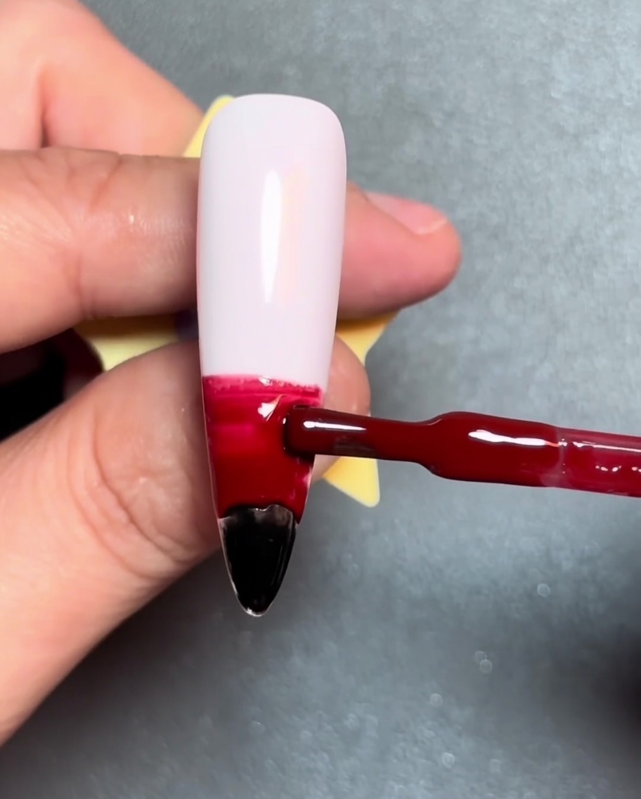 Un pennello applica una striscia orizzontale di gel arancione sopra il gel rosso.