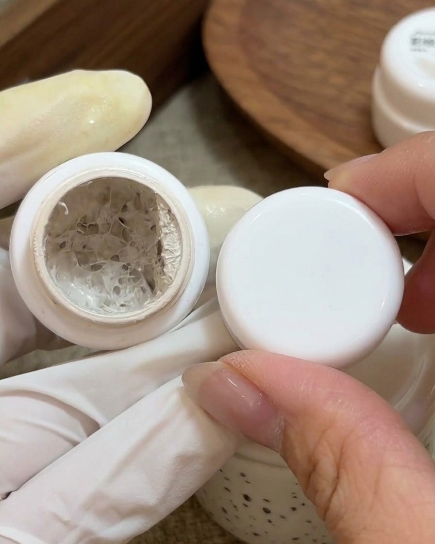 Un pennello piccolo applica gel color bianco latte sulla base di ununghia naturale preparata.
