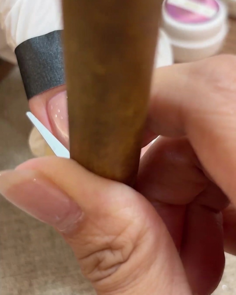 Primo piano di un piccolo strumento usato per modellare il gel cat eye in un arco perfetto da French tip sullunghia.