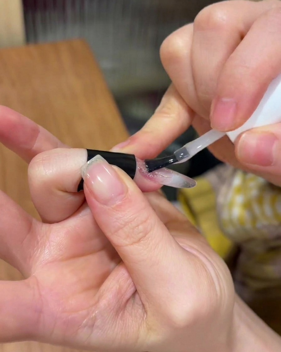 Applicazione di uno strato trasparente di gel costruttore sopra il design dellunghia esistente.