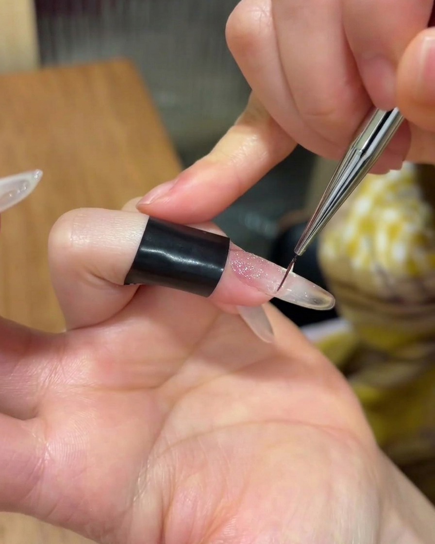Una piccola quantità di gel adesivo trasparente applicata al centro di ununghia.