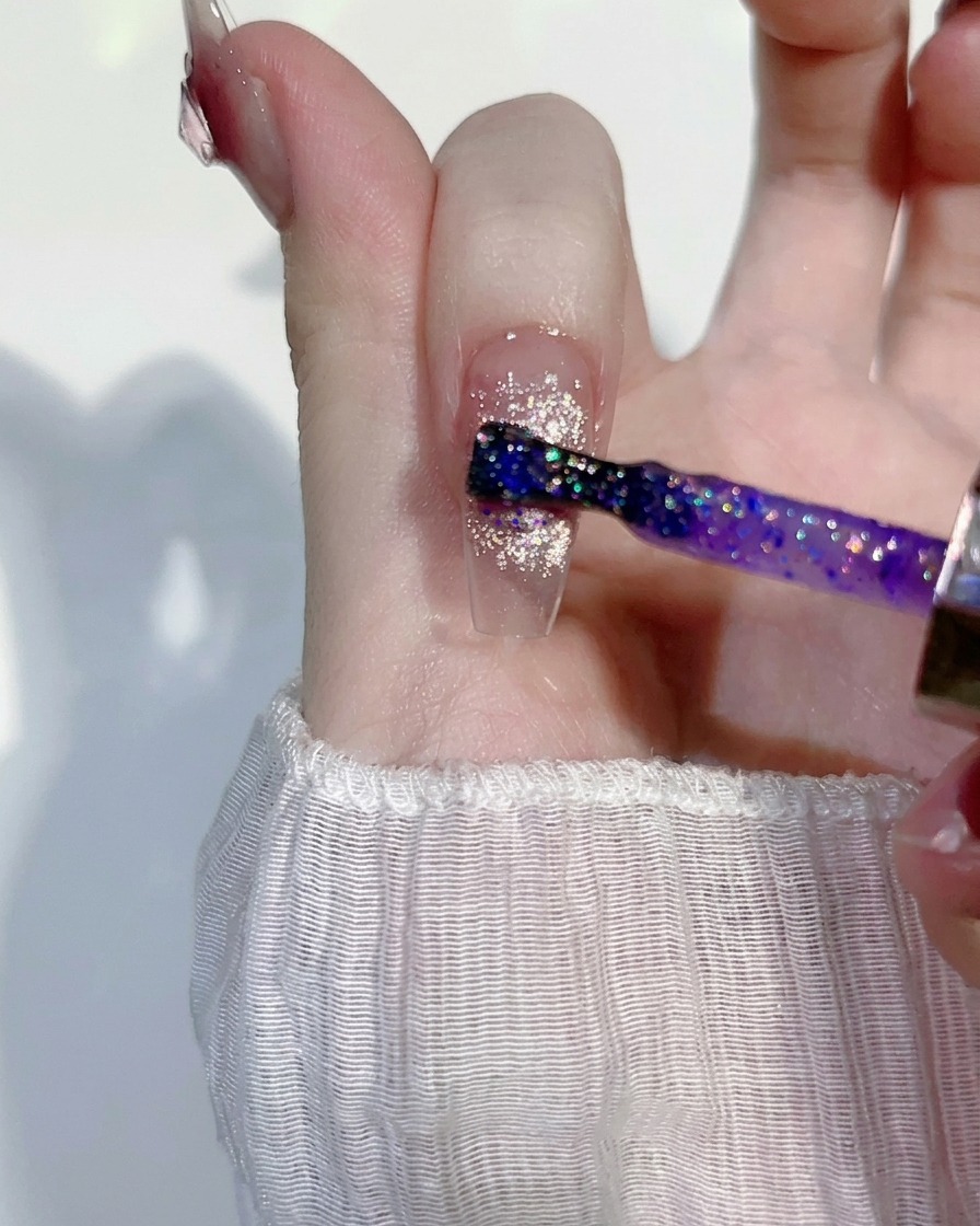 Uno strato sottile di gel glitterato dai riflessi viola applicato su un design cat-eye rosa.