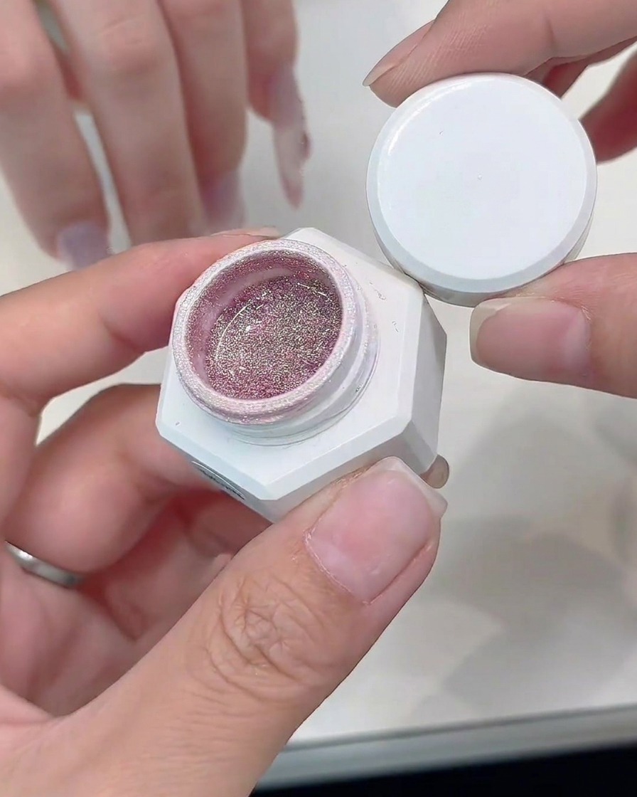 Un pennello di precisione applica gel glitterato argento lungo il bordo di una punta French cat-eye.