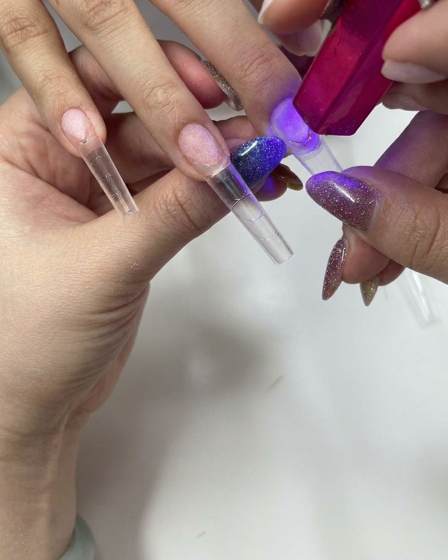 Utilizzo di una piccola lampada UV/LED portatile rosa per polimerizzare la tip press-on.