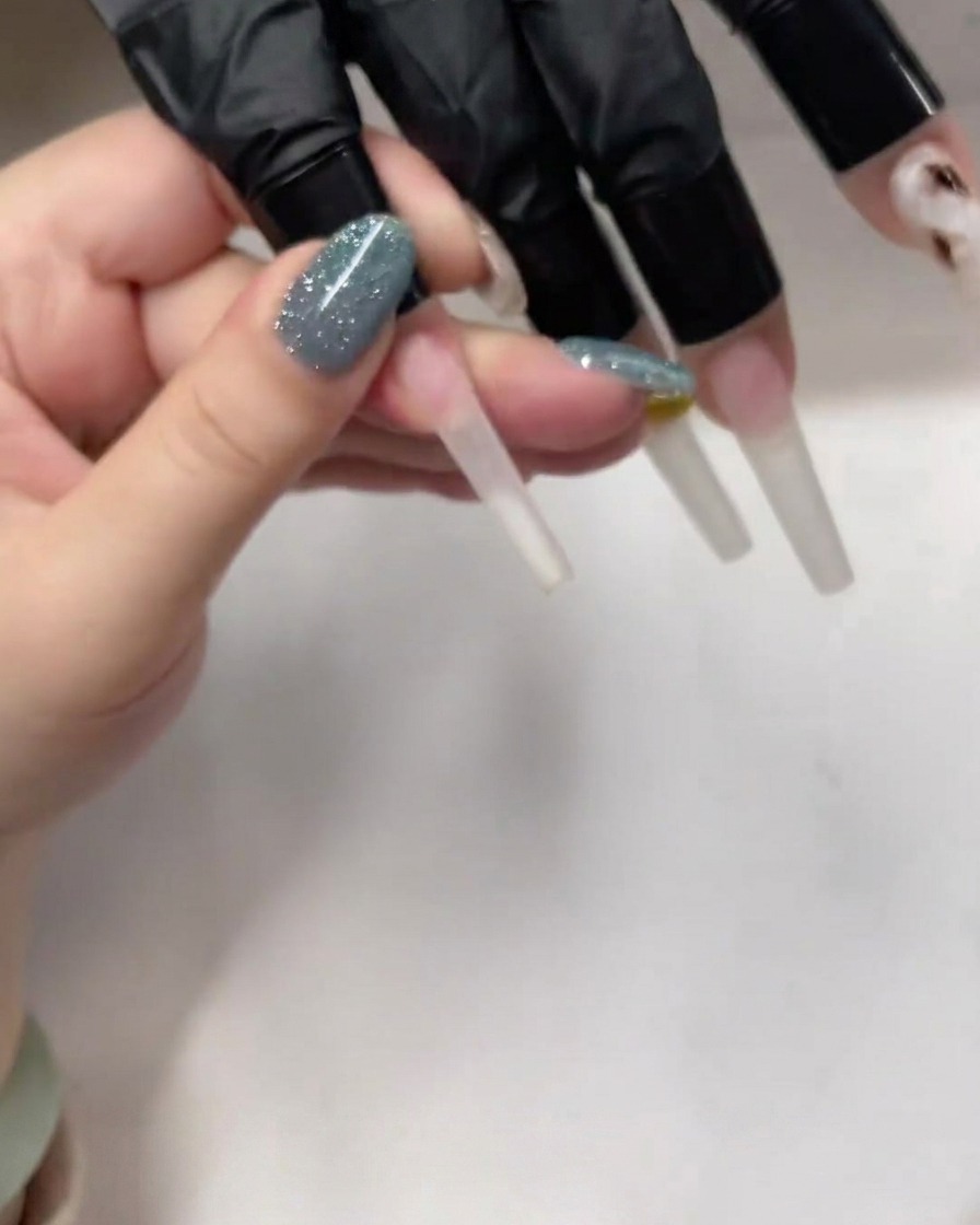Dettaglio di un pennello che applica uno strato sottile e trasparente di gel base su ununghia a ballerina.