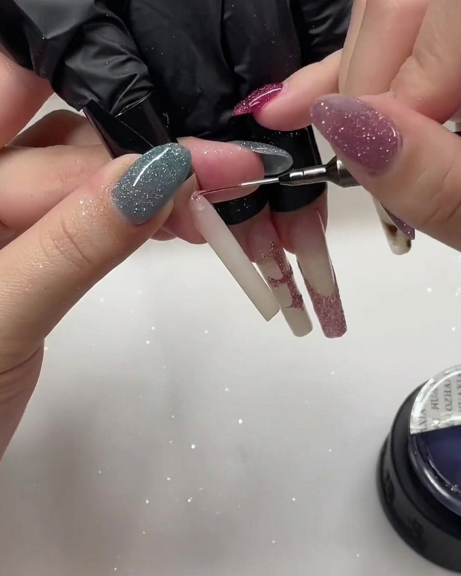 Primo piano di ununghia che riceve un ulteriore strato di polvere glitter rosa.