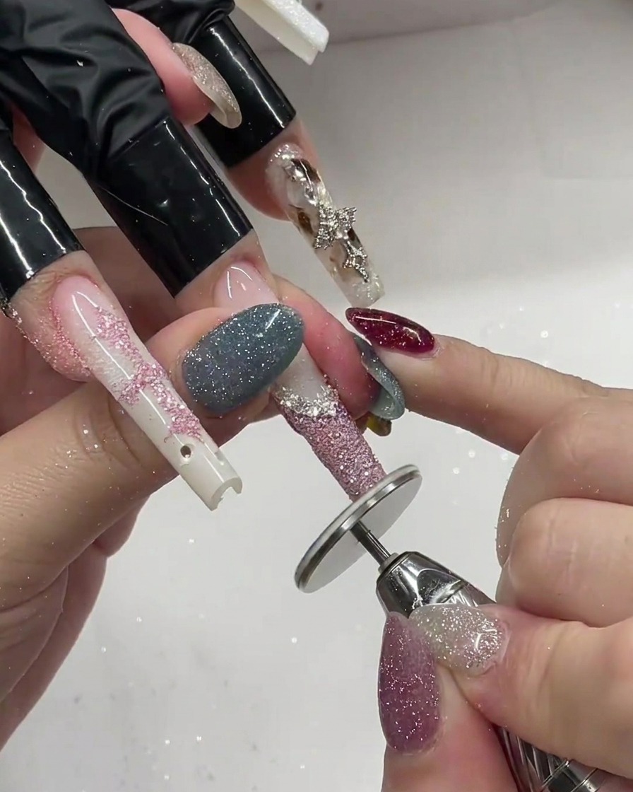 Un pennello applica polvere glitter rosa sopra una French gel bianca su unestensione.