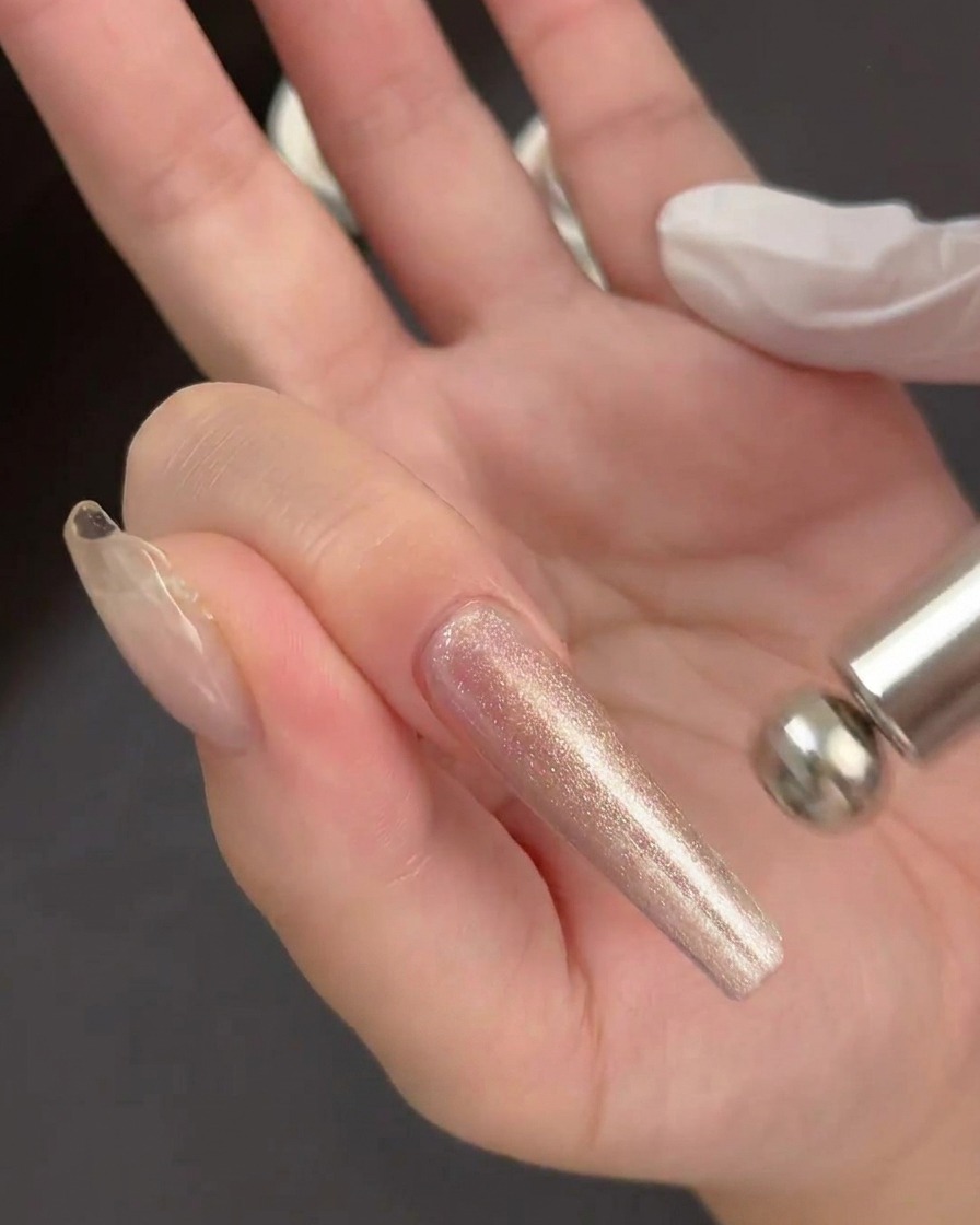 Una mano tiene un magnete cilindrico sopra unapplicazione di gel bagnato e scintillante su una tip trasparente.