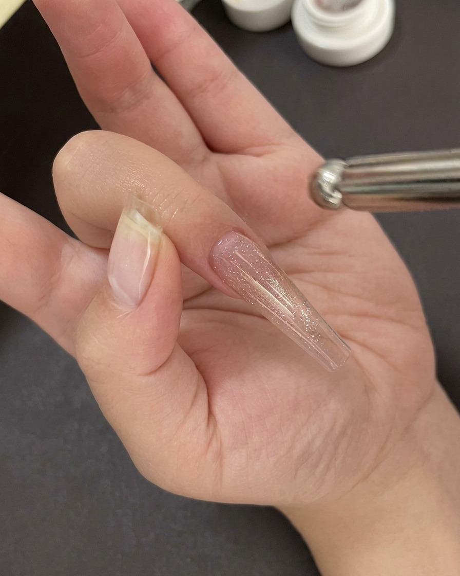 Una mano posizionata sotto una lampada UV/LED professionale per polimerizzare la base gel.