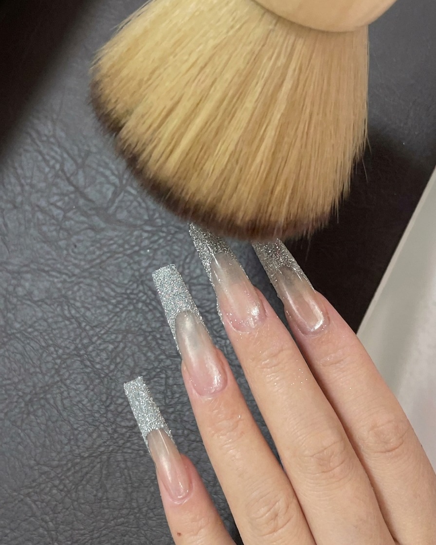 Un pennello morbido e soffice spazza via i residui di glitter dalla superficie delle unghie.