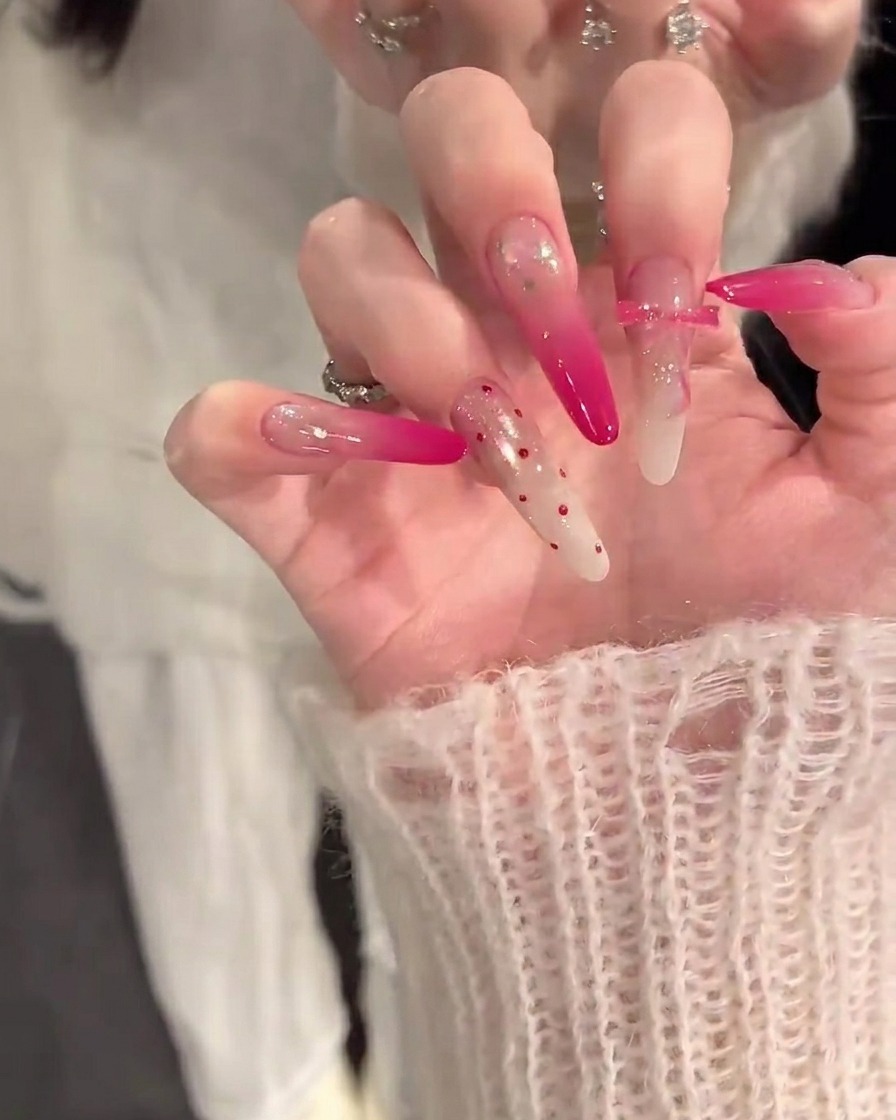 Primo piano di una mano che applica una base coat color nude su unghie pulite e preparate.