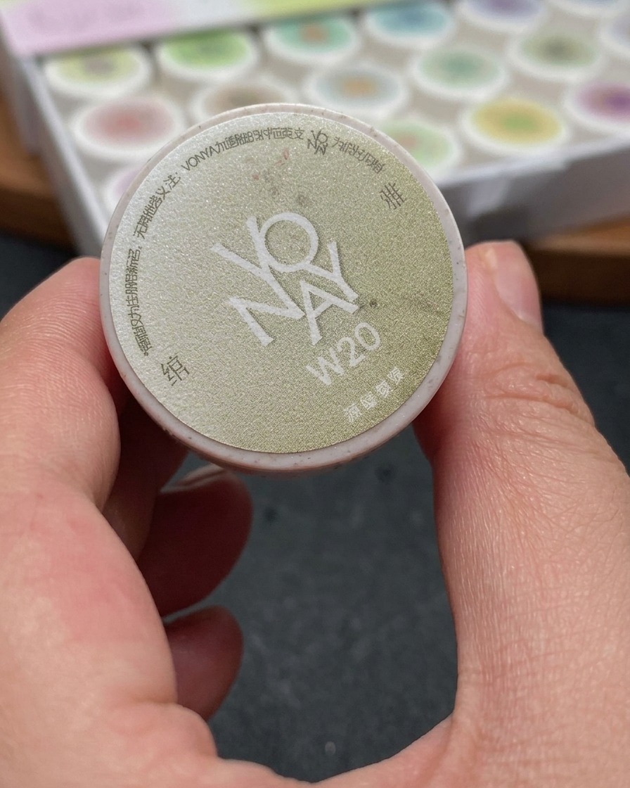 Un pennello che applica un gel cat-eye bianco scintillante su ununghia, coprendo uniformemente lintera superficie.
