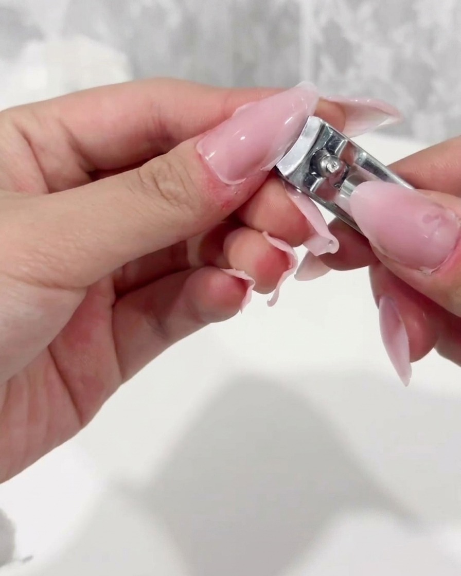 Un taglia tip professionale accorcia il bordo libero di una tip di plastica trasparente.