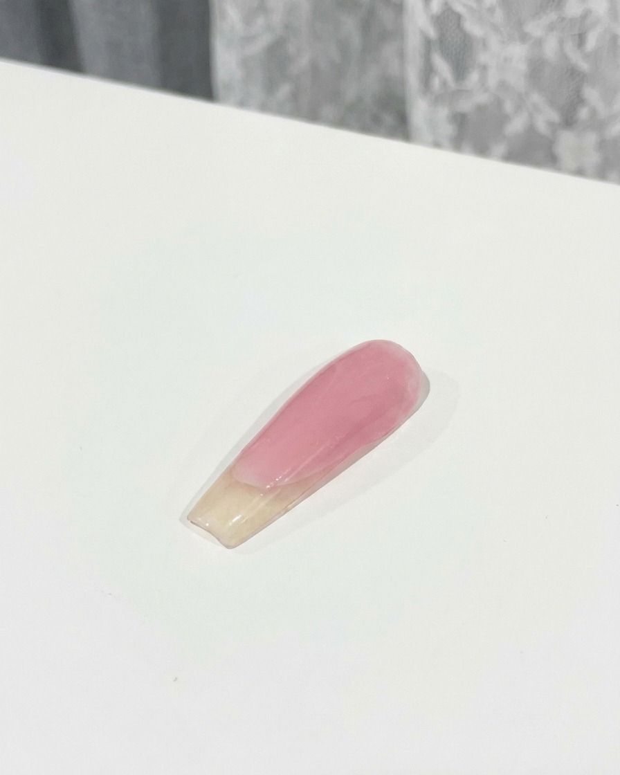 Un pennello che applica uno strato di top coat sopra un fiocco 3D rosa fissato su ununghia.