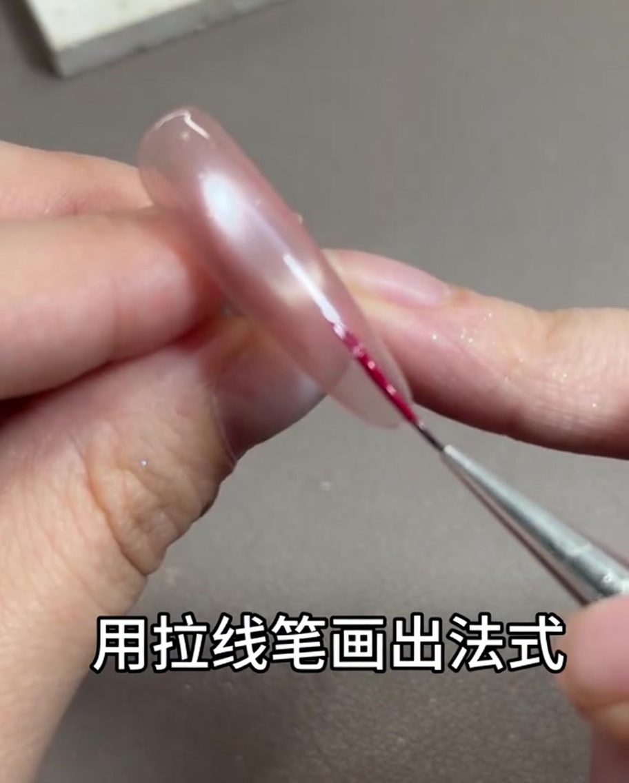 Un sottile pennello liner per nail art che traccia una delicata linea rosso rosa lungo il bordo libero dellunghia.