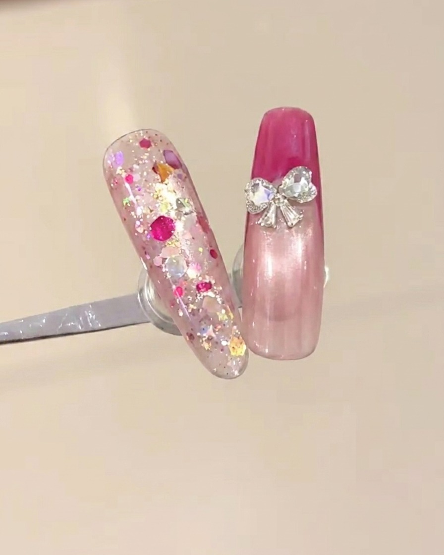 Due piccoli strass a forma di cuore posizionati alla base della french tip per creare un design a fiocco.