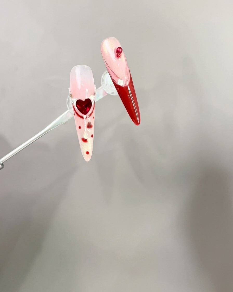 Pinzette che posizionano un fiocco rosso 3D su una punta di ununghia curata.