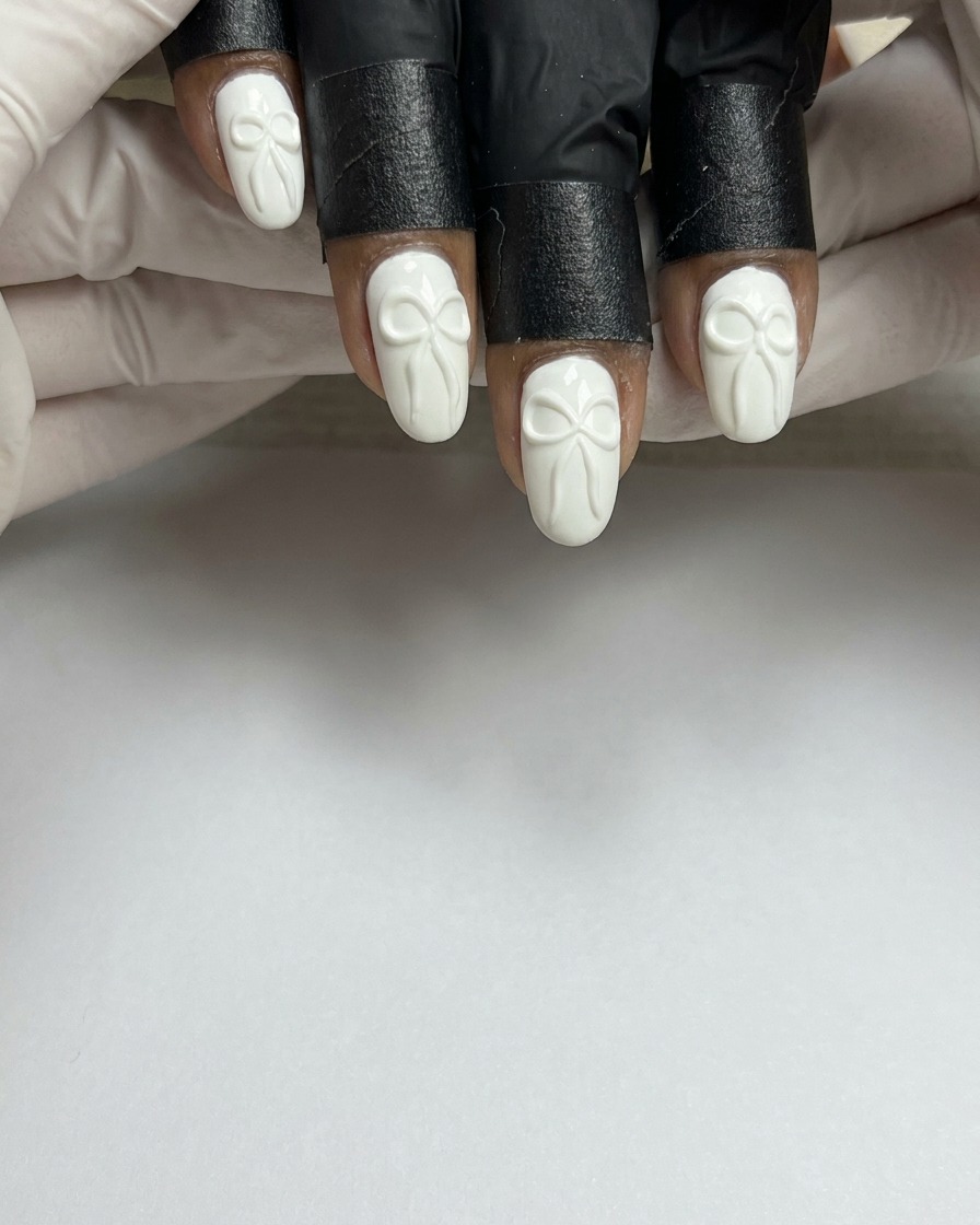 Un pennello per unghie applica uno strato uniforme di smalto gel bianco su ununghia naturale preparata.