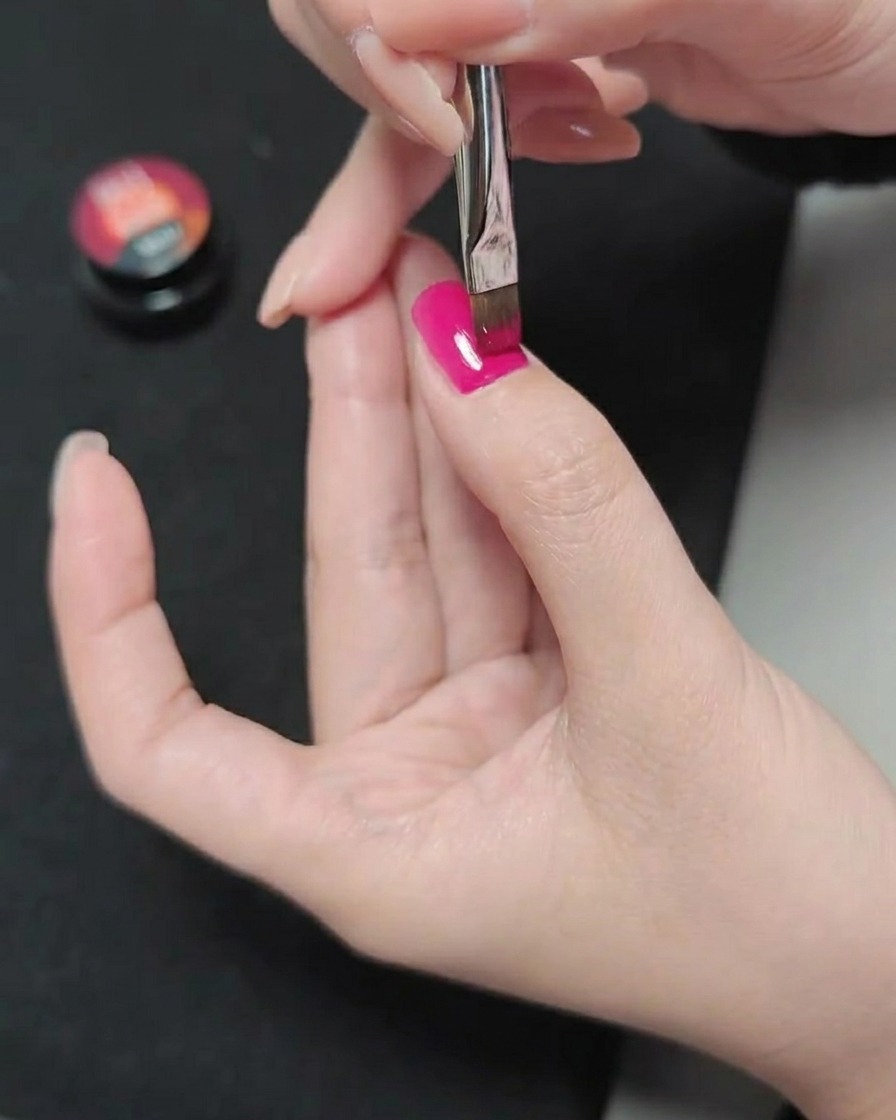 Un pennello applica un terzo strato di gel magenta, creando una finitura liscia e satura di colore.