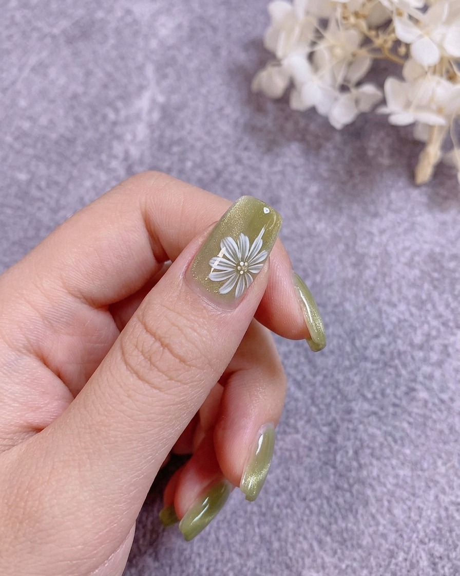 Un pennello applica un top coat trasparente e resistente sopra una nail art floreale dipinta.