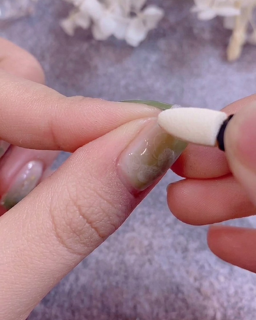 Un applicatore in silicone per ombretto viene utilizzato per stendere polvere cromo metallizzata su ununghia in gel.