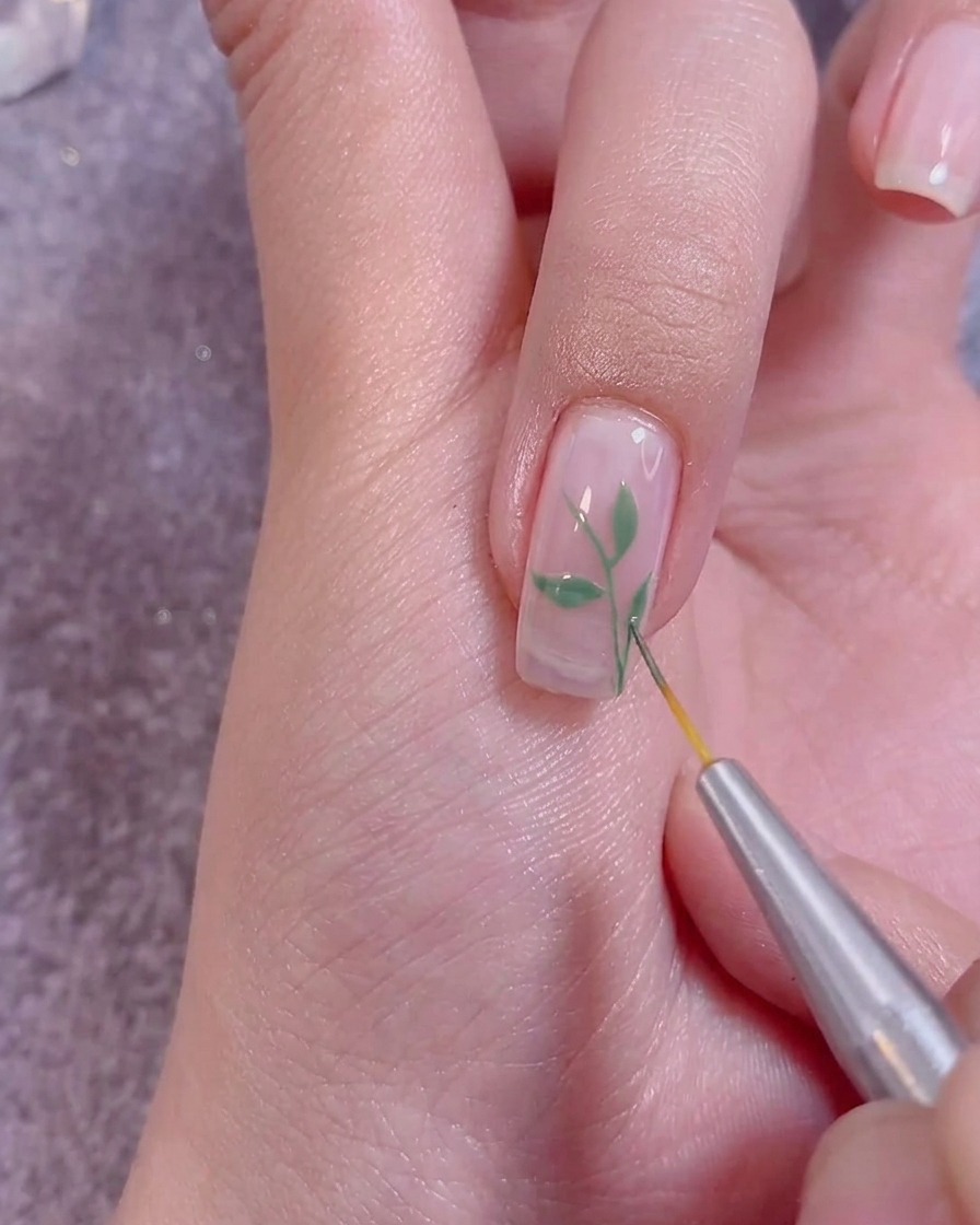 Applicazione di un top coat trasparente sopra la nail art finita con un pennello professionale.