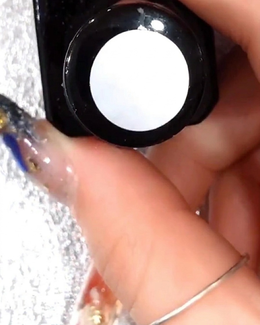 Primo piano di un pennello che applica un sottile strato di gel trasparente sui petali bianchi già realizzati.