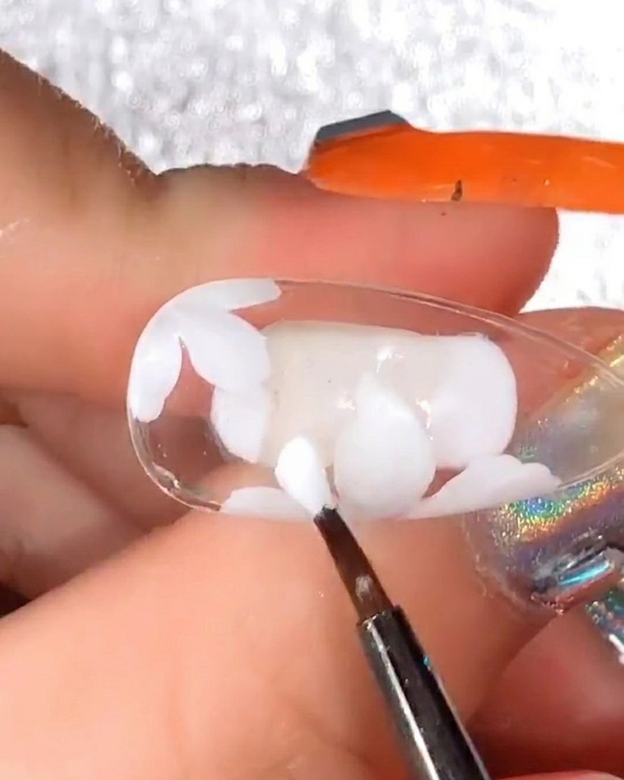 Pennello di precisione che aggiunge altri petali in gel bianco sopra il design polimerizzato per aumentare il volume.