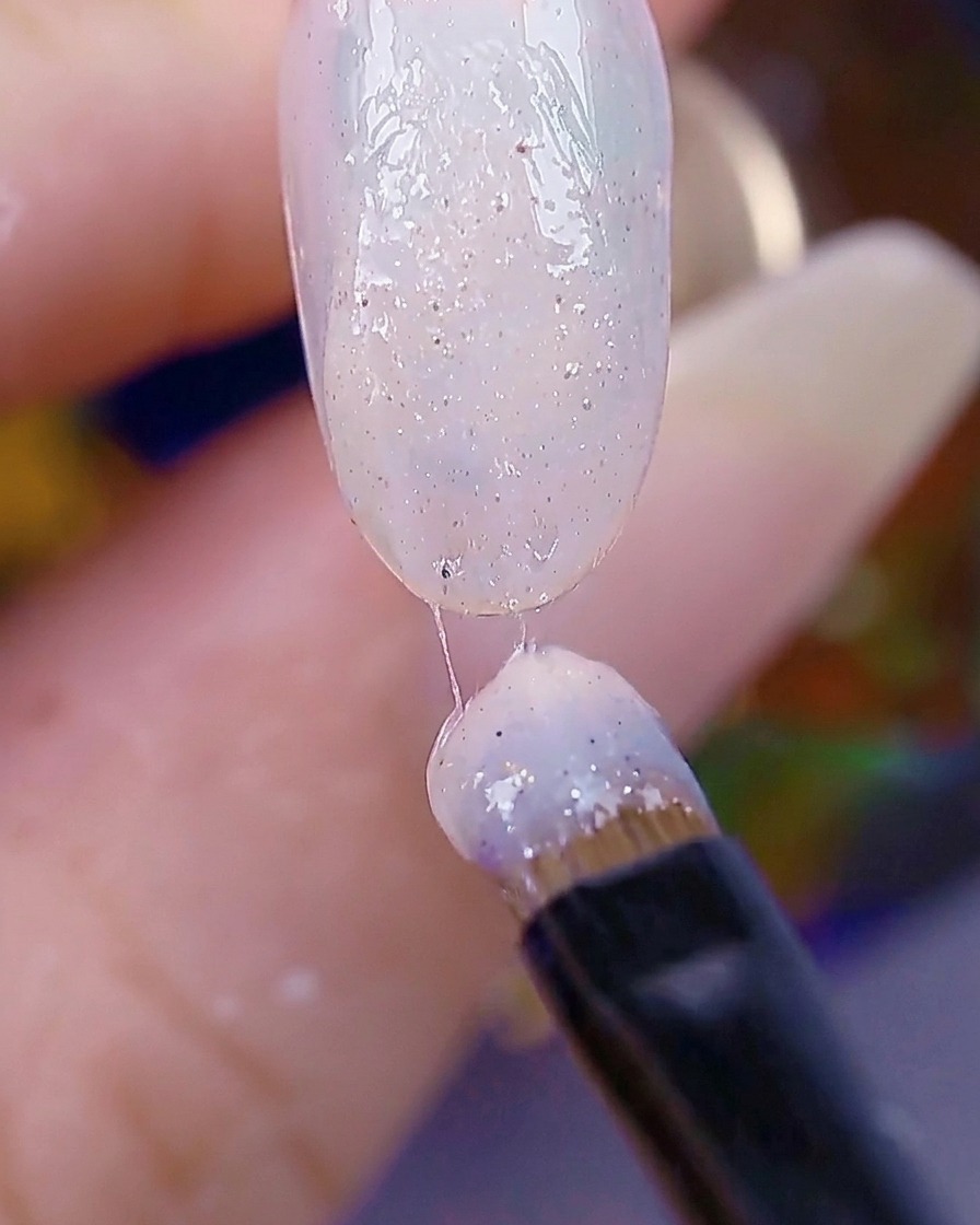 Un pennello applica un secondo strato di gel con texture di zucchero, con la superficie dellunghia che appare testurizzata e pronta per la polimerizzazione.